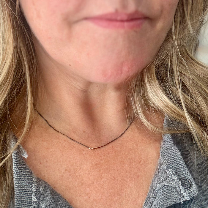 close-up image of female model wearing handmade necklace with 3 tiny 14K yellow gold wire hearts on oxidized sterling silver chain