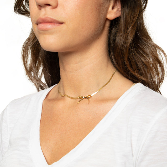 Model wearing mini bow necklace in gold